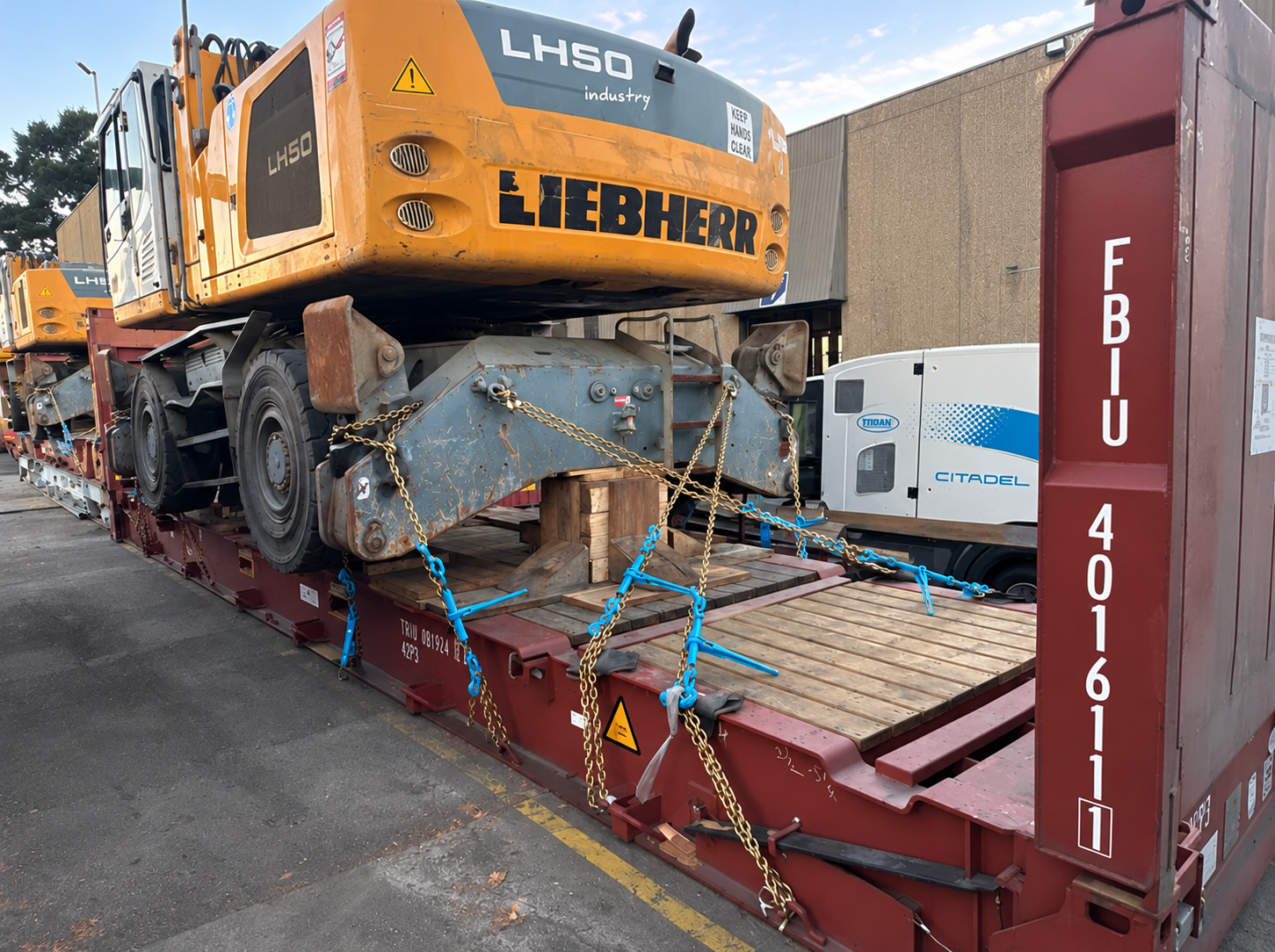 Chain lashing and timber supports securing a used excavator